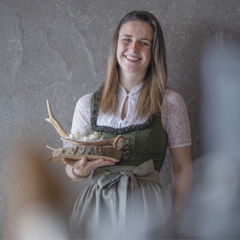 wild o’williams Seiser Alm – Gastgeber Jessica im Dirndl mit Williamsschnaps in der Hand